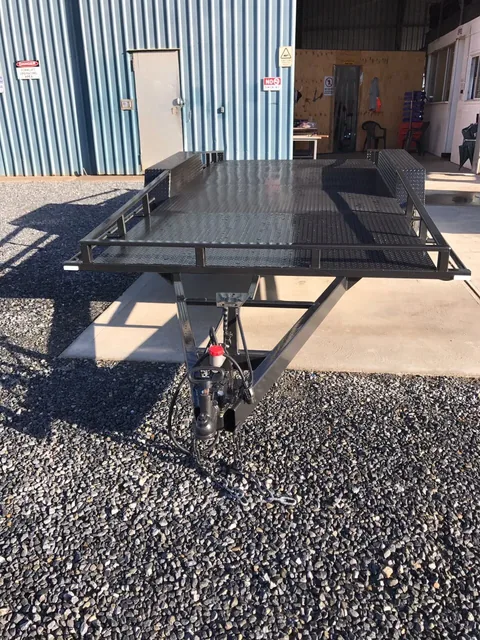 Close-up of tandem axle wheels with white rims on black 16ft car trailer.