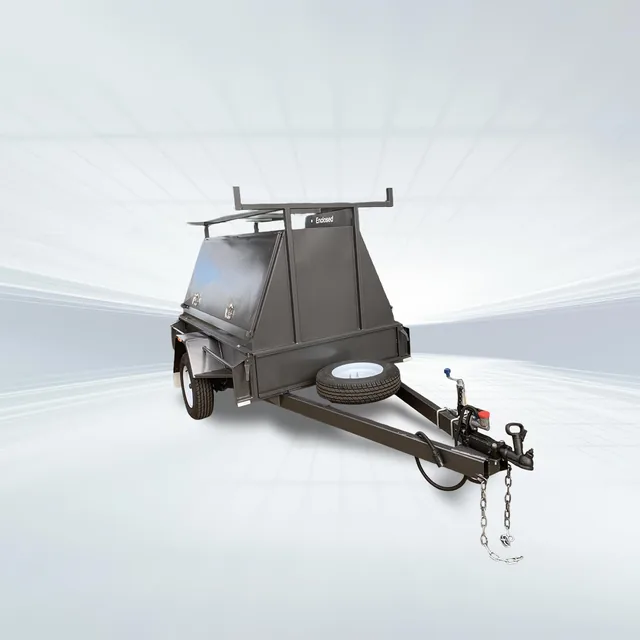 Studio side angled view of black 7x5 tradesman trailer with enclosed canopy and roof rack on white background.